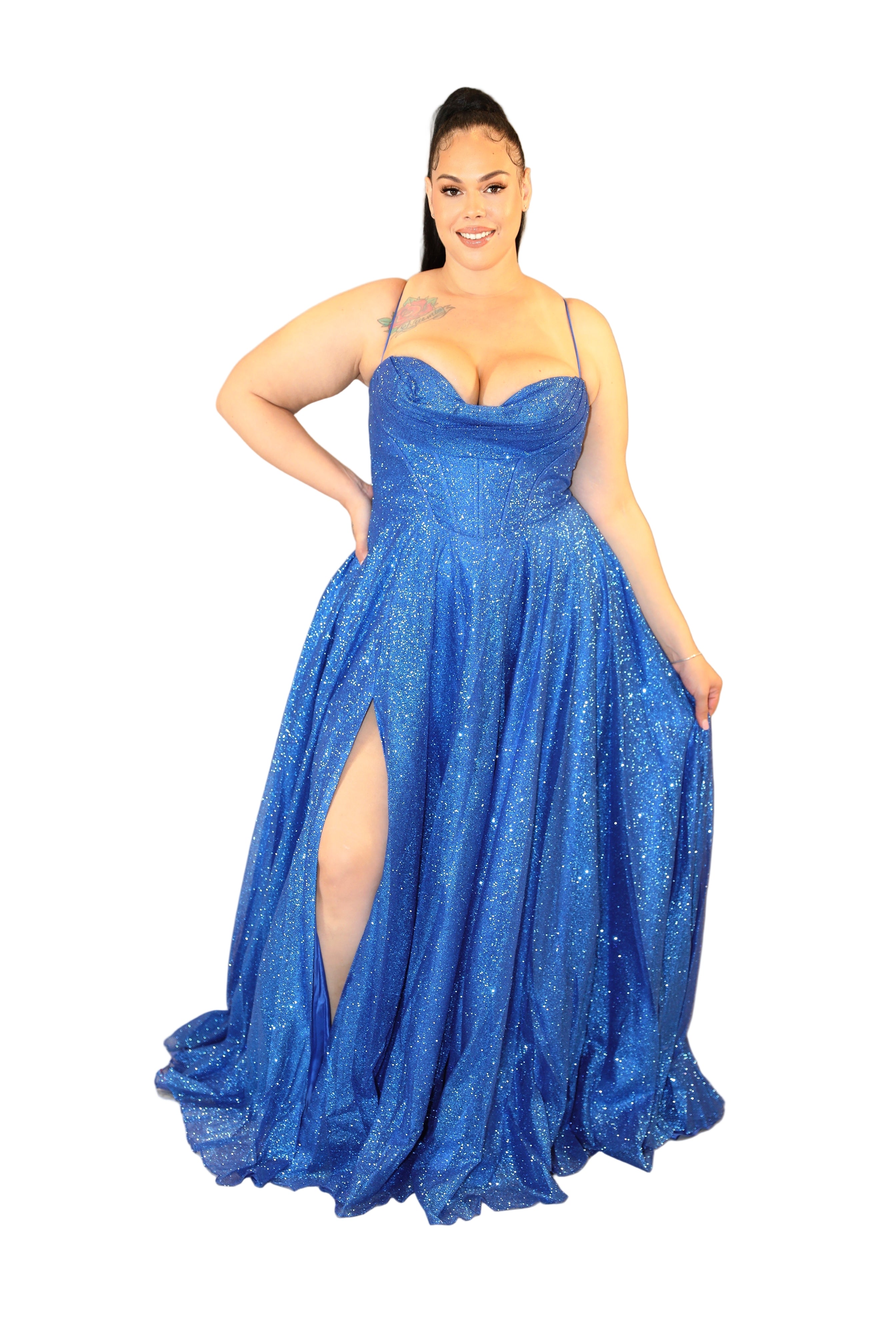 Woman wearing a blue sparkly evening gown with a slit on a plain background