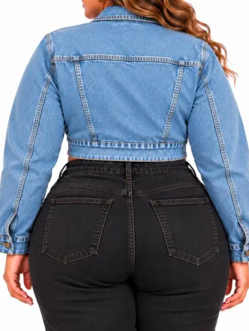 A woman shown from the back wearing a cropped light blue denim jacket and black jeans against a plain white background.