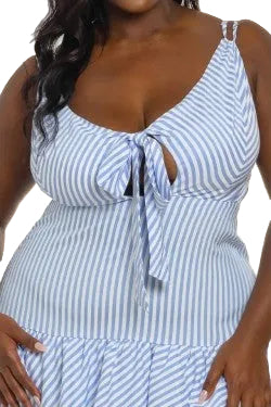 Woman wearing a blue and white striped dress with a tie in the bust against a white background