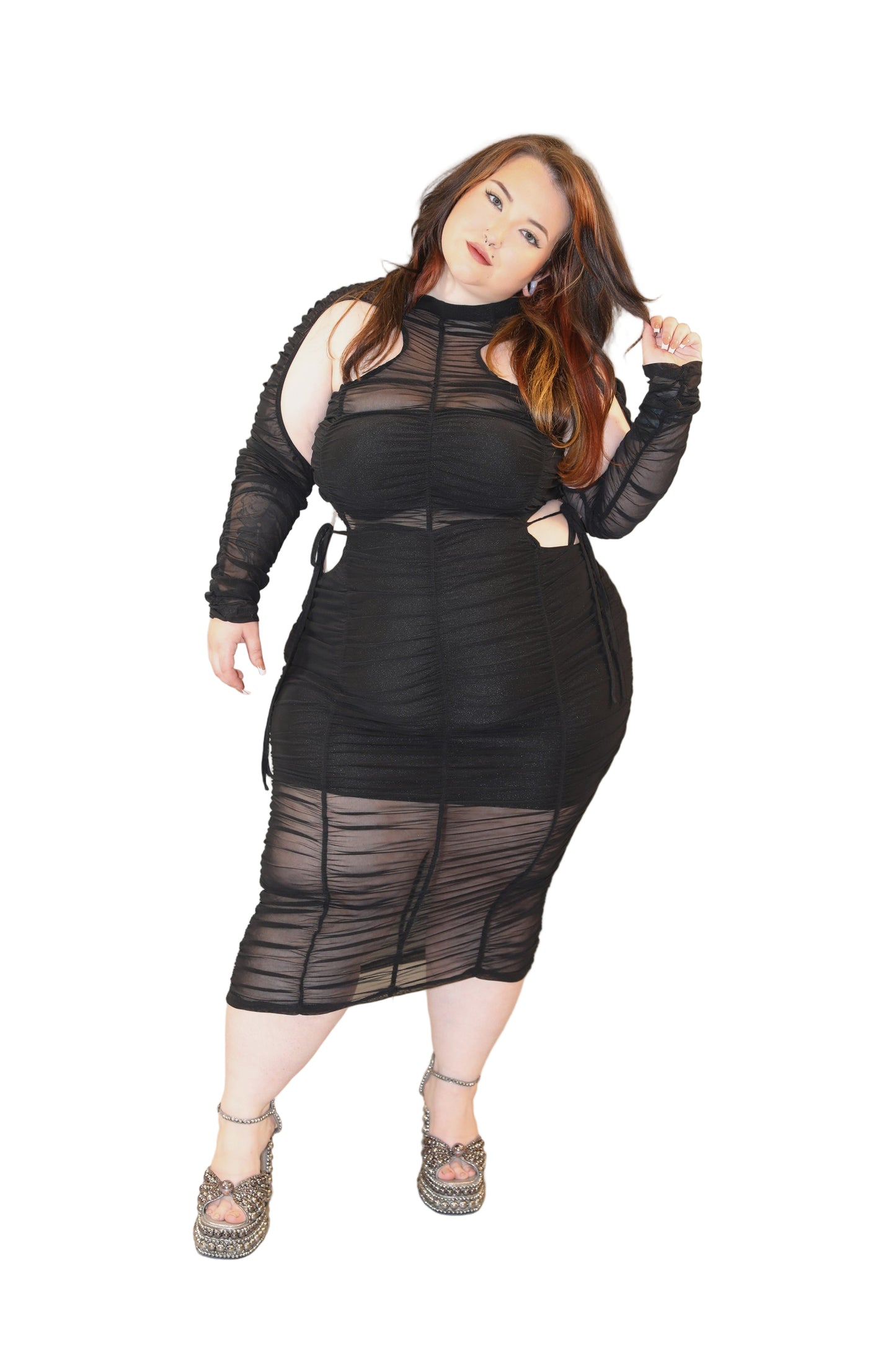 Person wearing a black sheer dress with long sleeves on a plain background
