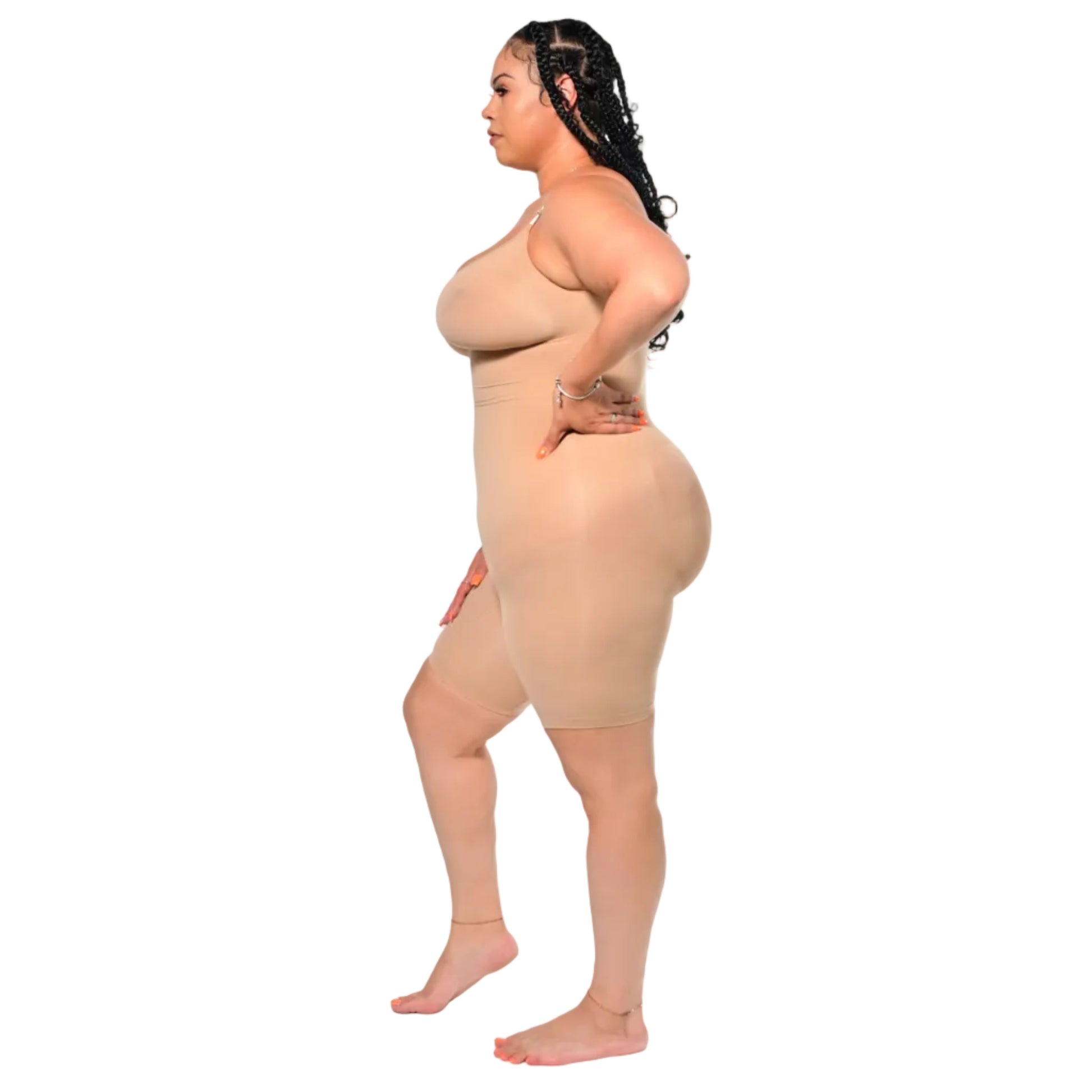 Woman wearing a beige shapewear bodysuit on a white background with her hand on her hip (left side)