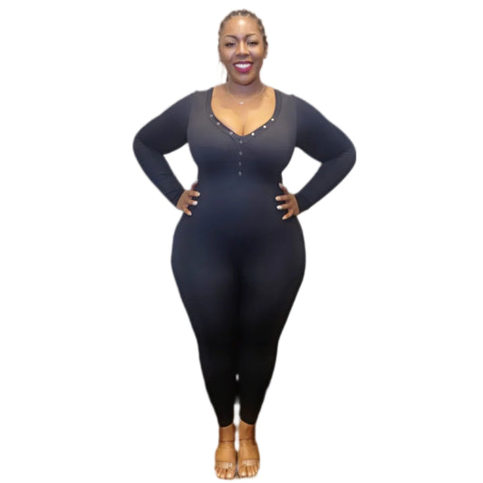 Woman wearing a black long-sleeve catsuit with a v-neck with snaps on a white background.