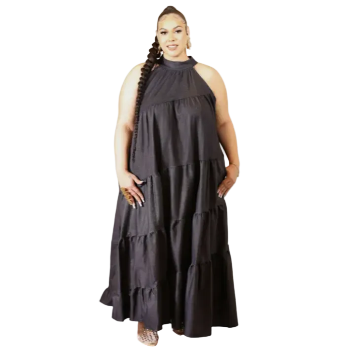 Woman wearing a dark denim halter neck dress with ruffled layers on a white background. (front)