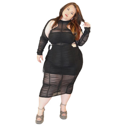 Woman wearing a black sheer dress with cutouts on a white background (front)
