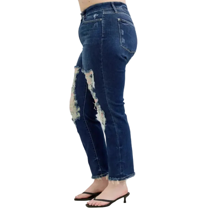 Woman wearing distressed dark wash blue jeans on a white background (left side)
