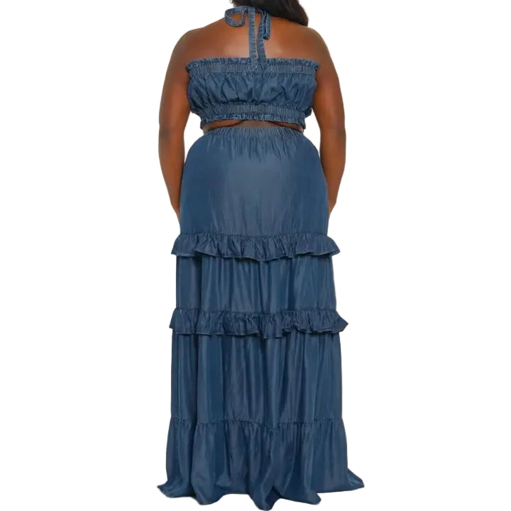 Woman wearing a blue denim bandeau and skirt set with ruffled layers on a white background