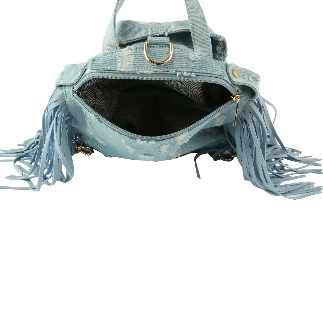 Light blue denim bag with backpack straps, a handle, fringe, and gold hardware on a white background. (inside)