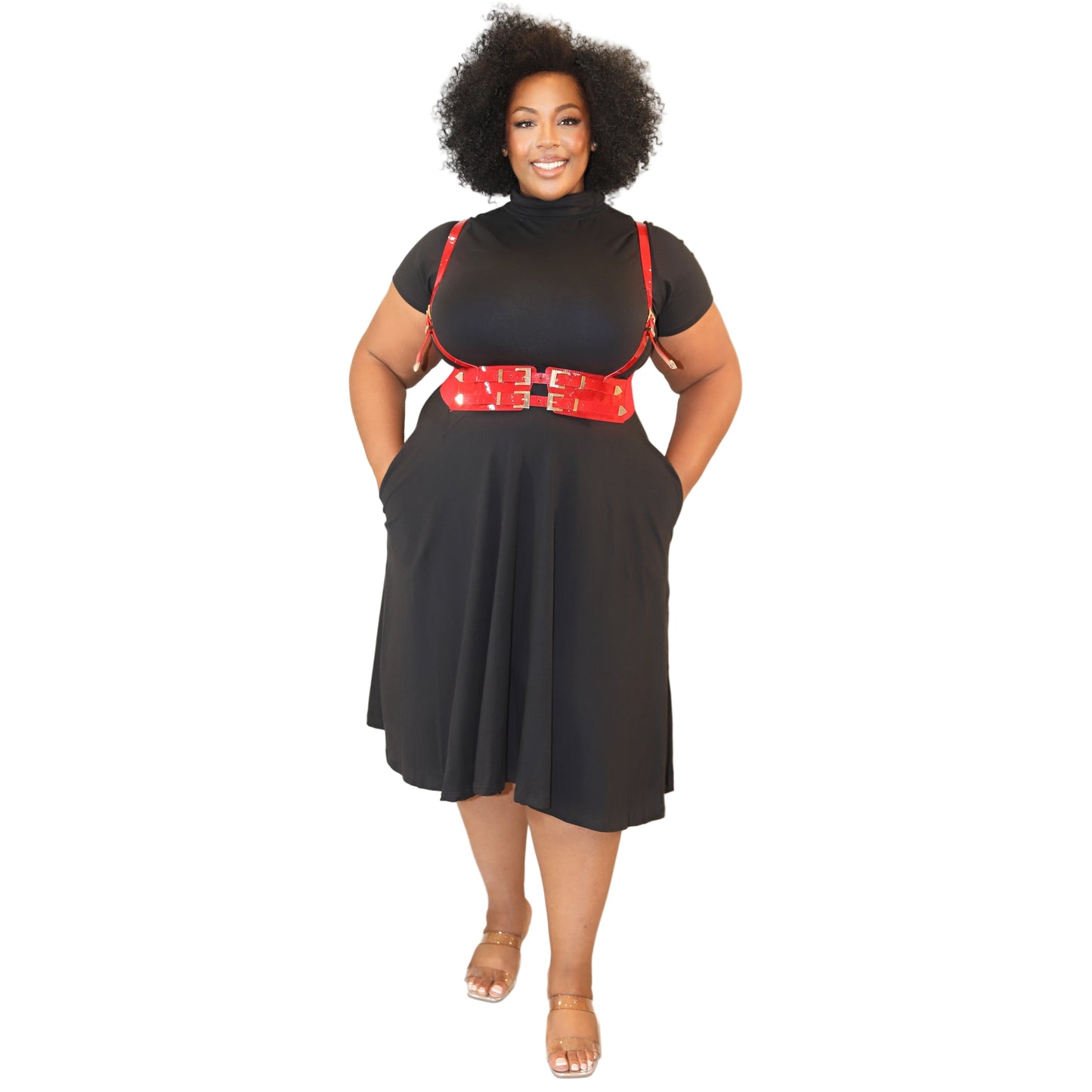 Woman wearing a black dress with a turtle neck and short sleeves, and a red harness with gold accents on a white background