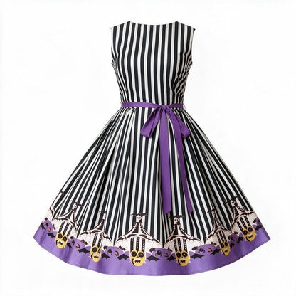 A sleeveless retro-style swing dress with black and white vertical stripes, a purple waist tie, and a purple hem featuring a graveyard pattern with skulls, bats, and skeletons.