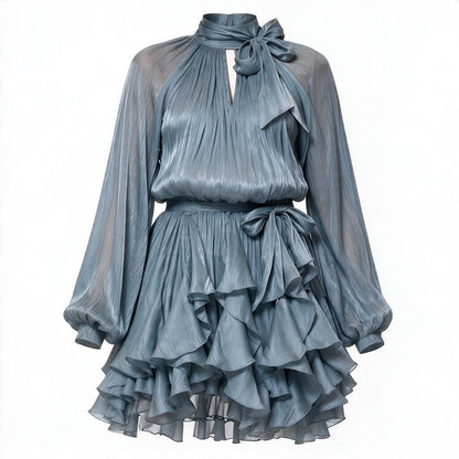 A dusty blue-gray mini dress with a high neck, large bow at the collar, long balloon sleeves, a matching waist tie, and a tiered ruffled skirt, shown on a plain white background.