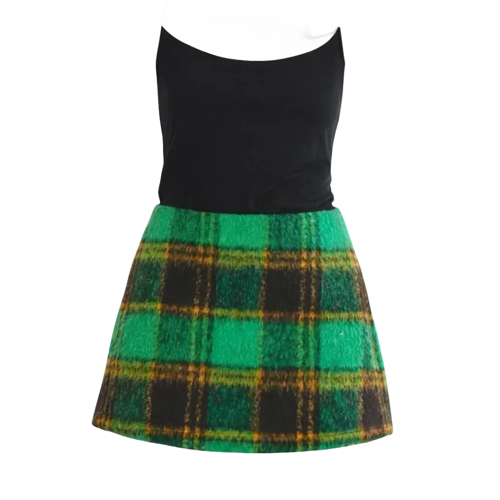 Black tank top with a green plaid skirt on a white background