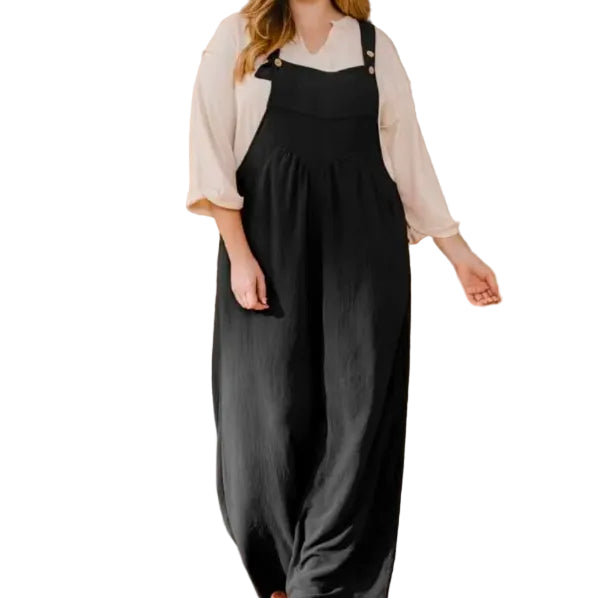 Woman wearing a white shirt and black overalls on a white background.